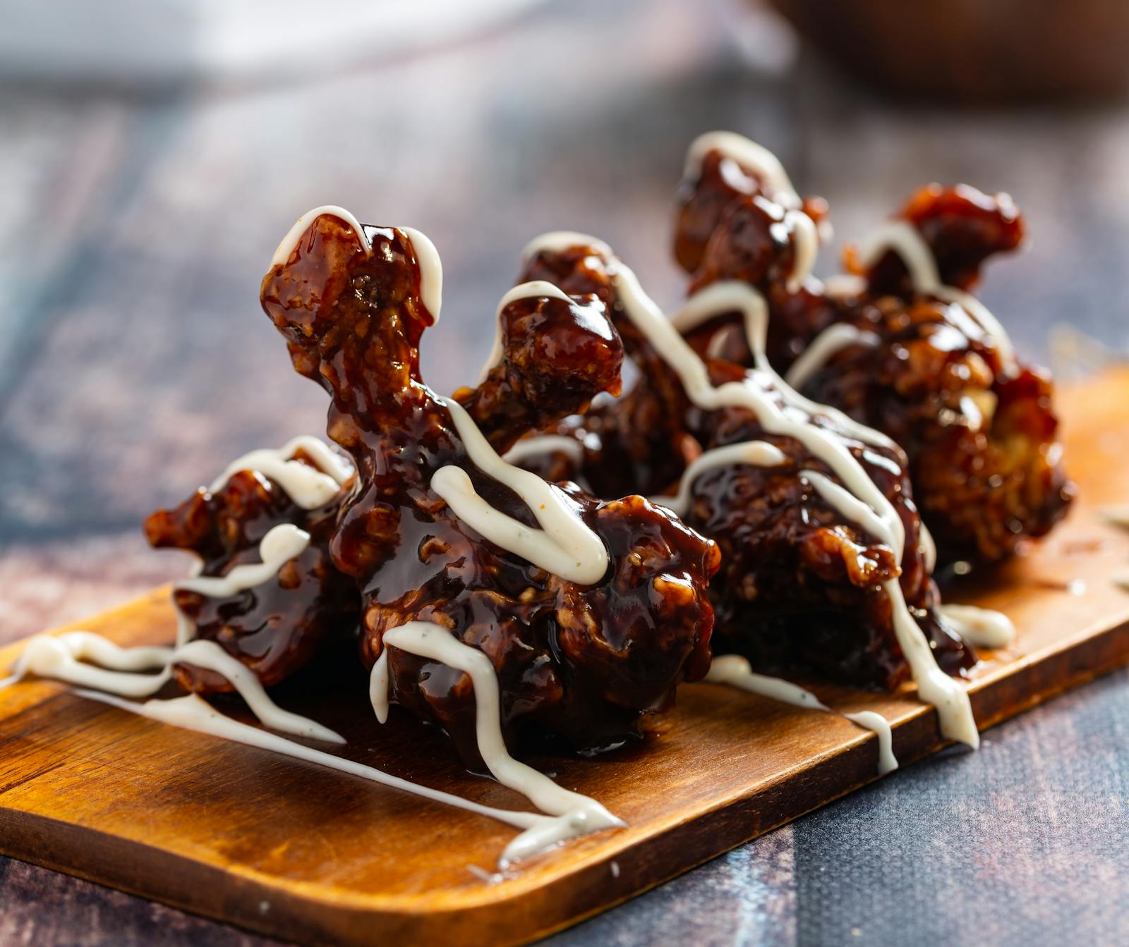 In huisglazuur gelakte kippendij met witte saus-drizzle op houten plank