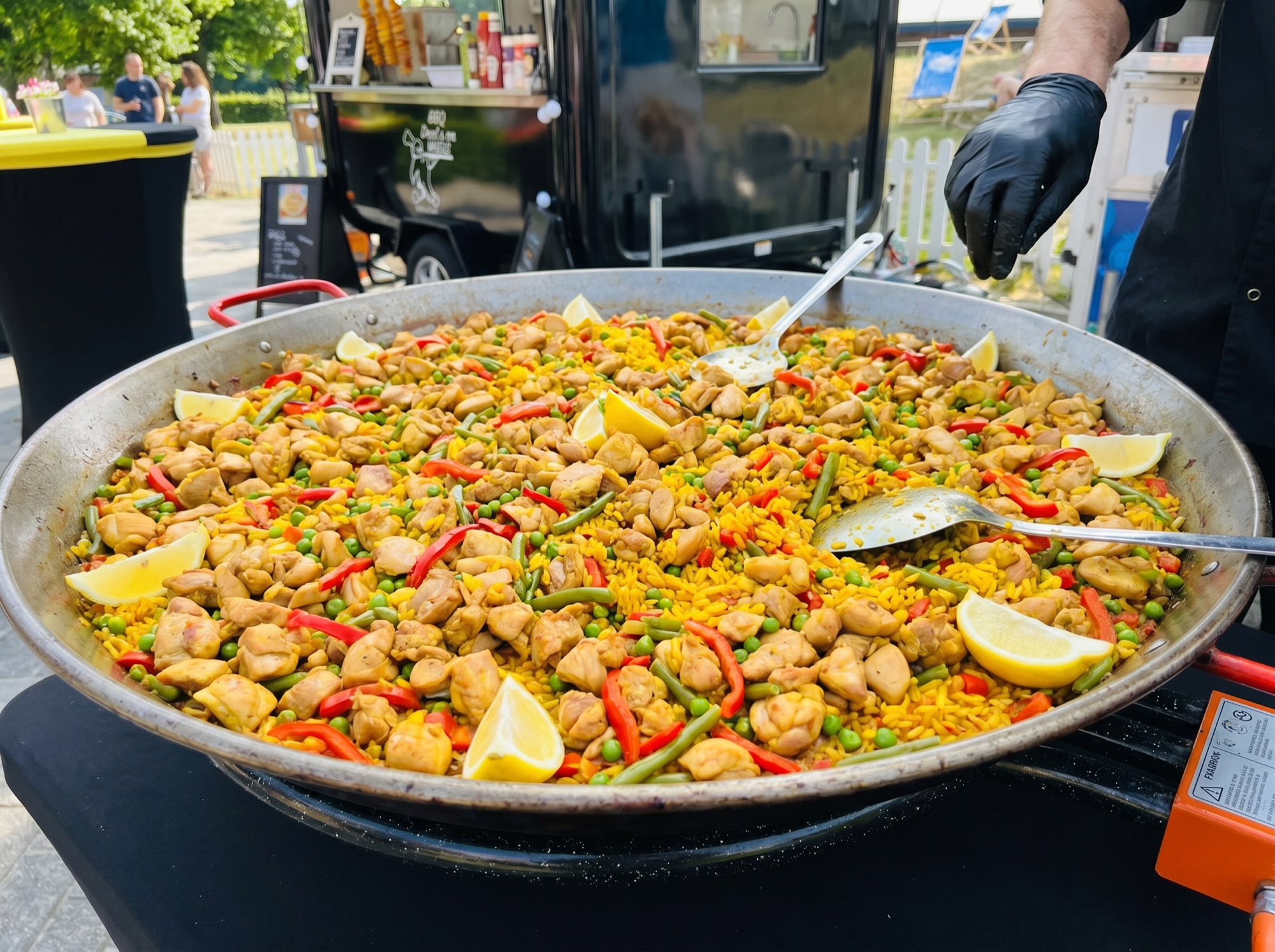 Paella met kleine stukjes malse kippendij in safraanrijst, bereid aan de foodtruck