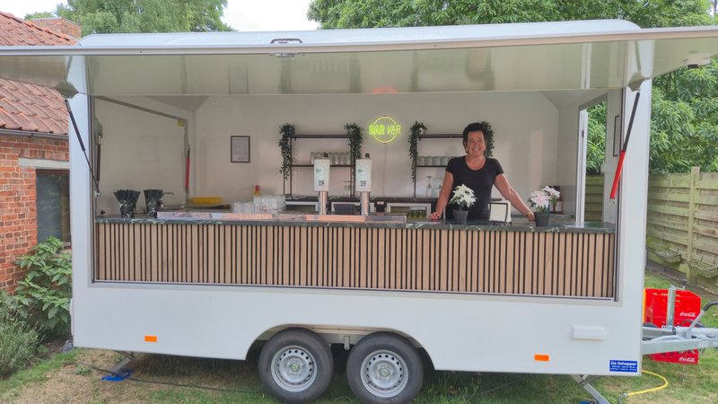 Witte vintage Bar-Kaar trailer opgesteld op een eventlocatie